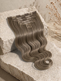 Wavy clip-in hair weft sample in ashy brown tone with comb clips.