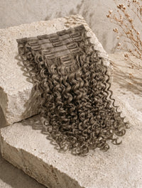 Curly clip-in hair weft sample in ashy brown tone with comb clips.