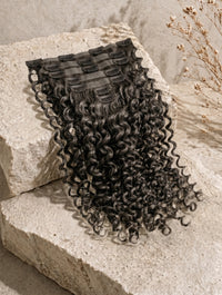 Clip-in hair extension weft in black curly texture with attached snap clips