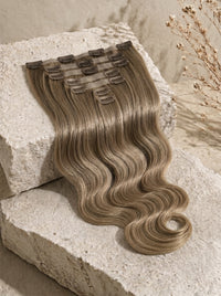 Seamless clip-in hair extensions with dark blonde body wave hair and visible snap clips