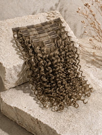 Seamless clip-in hair extensions with dark brown curly hair and visible snap clips