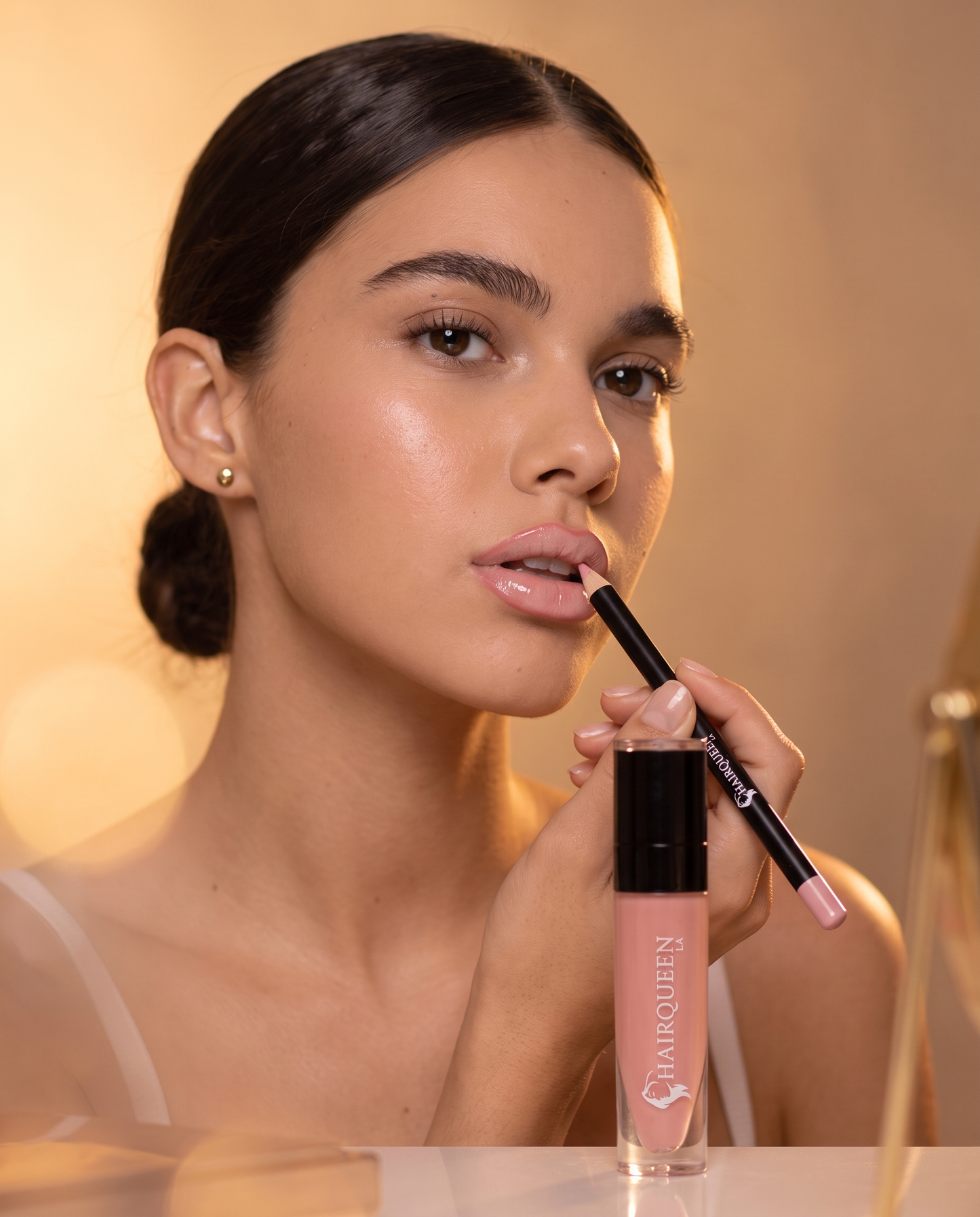 Liquid lip gloss applicator applying pink nude shade, glossy lips close-up