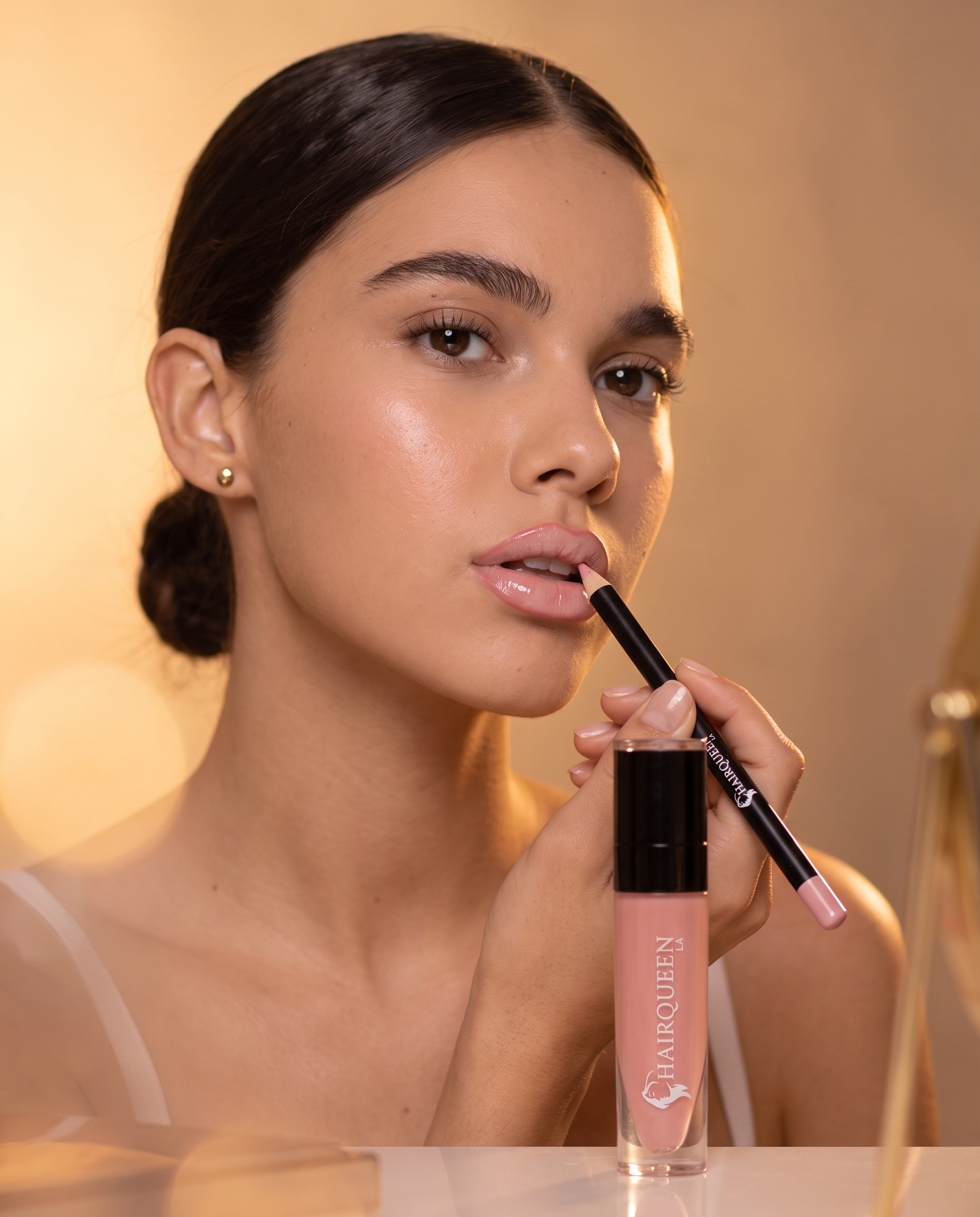 Liquid lip gloss applicator applying pink nude shade, glossy lips close-up