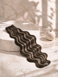 Dark wavy hair extension bundle with highlights, laid in a long layered strip