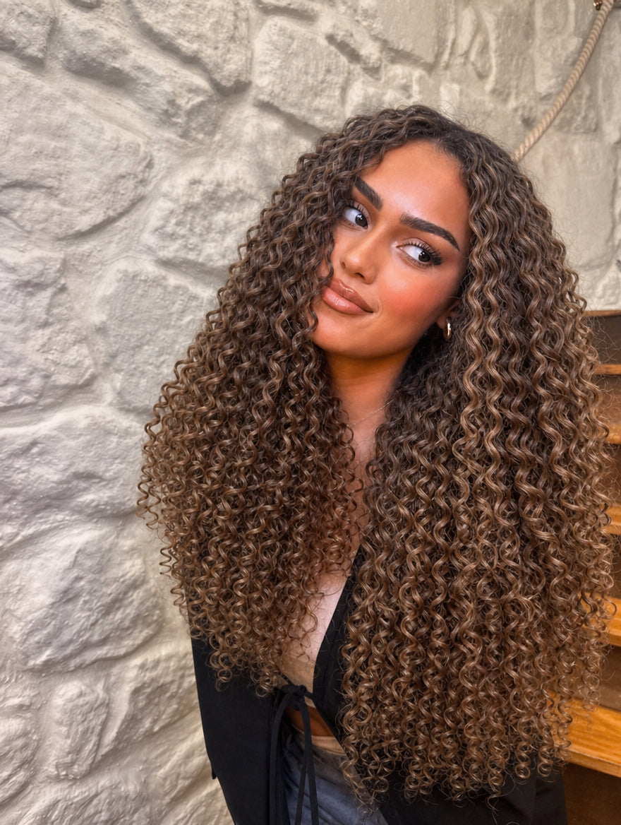 Long tight curly hair in dark brown with voluminous ringlets on model