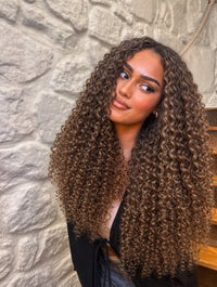 Long tight curly hair in dark brown with voluminous ringlets on model