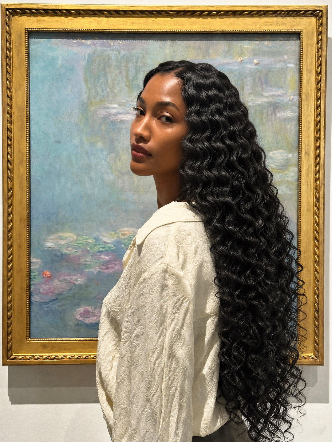 Long dark wavy hair extensions in bundles, worn straight-back over the shoulder.