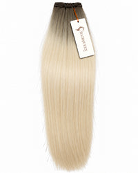 Hair extension weft in pale blonde, straight silky strands with dark top.