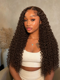 Curly tape-in extensions in deep black, long tight curls with full volume.