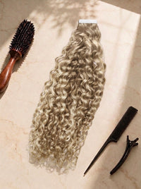 Curly tape-in hair extensions in pale blonde, springy ringlet curls with adhesive strip.
