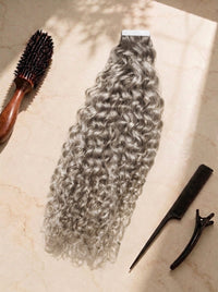 Curly tape-in hair extensions in silver ash, bouncy ringlet curls with adhesive strip.