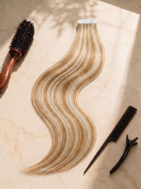 Straight tape-in hair weft, honey blonde with darker roots and soft wavy pattern.