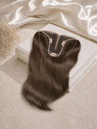 Hair topper on box base with dark hair extensions and clip attachments visible.