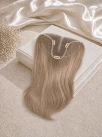 Light blonde hair topper with U-shaped clip base laid on a satin cloth