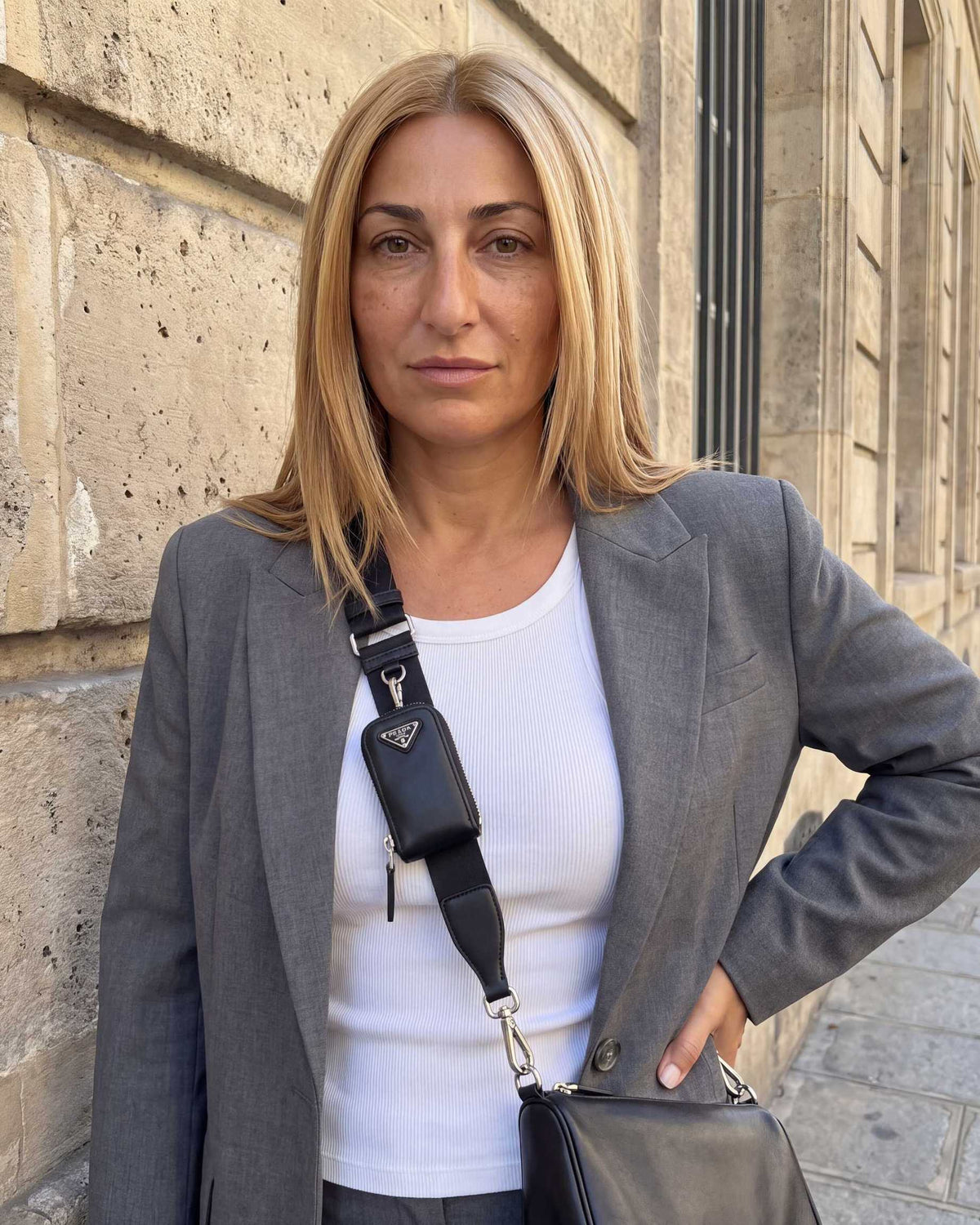 Gray blazer over a white T-shirt with black strap accessory and mono cover topper