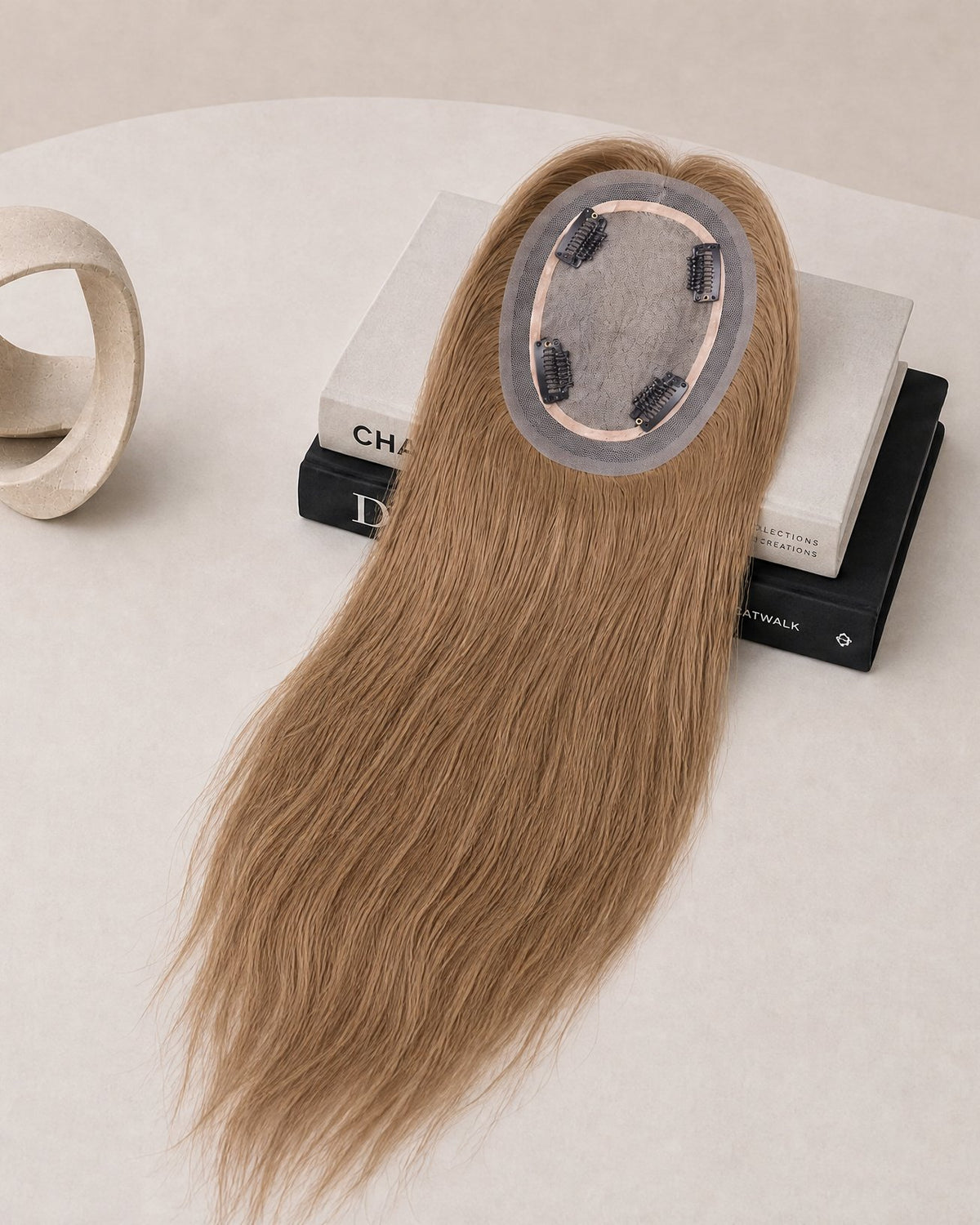 Light blonde hair topper with oval lace base and attached clips, top view.