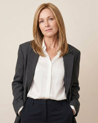 Model wearing blonde hair topper over white blouse and dark blazer.
